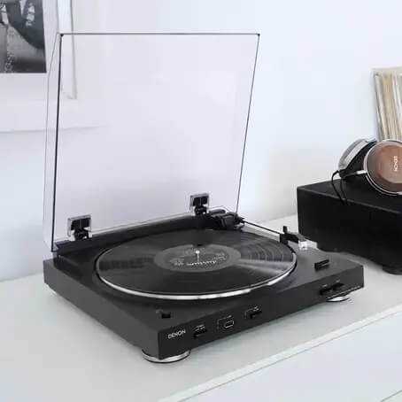 Um dos melhores toca-discos e um headphone marrom ao fundo em uma mesa branca.